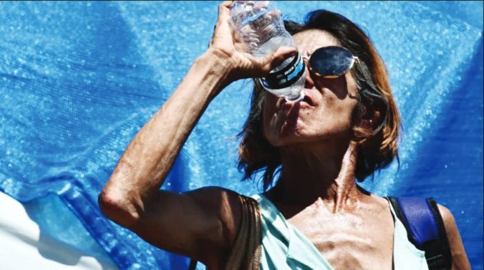 A woman drinks water while cooling down in a tent. An unusually early heatwave is building across the south-western United States, bringing temperatures more typical of early summer than mid-March. AFP
