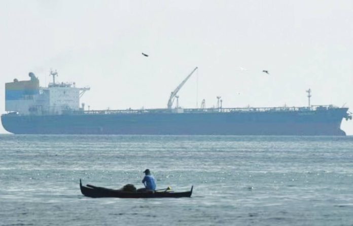 biz groups copy A fisherman paddles before the Sierra Leone-flagged Sara Sky, which is carrying crude oil from Russia, anchored at Limay port, Bataan province on March 26, 2026. AGENCE FRANCE-PRESSE