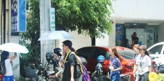 In Iloilo City, many people use umbrellas to shield themselves from intense heat while walking along busy streets. The Department of Health urges the public to stay alert and take precautions against heat-related illnesses. AJ PALCULLO/PN