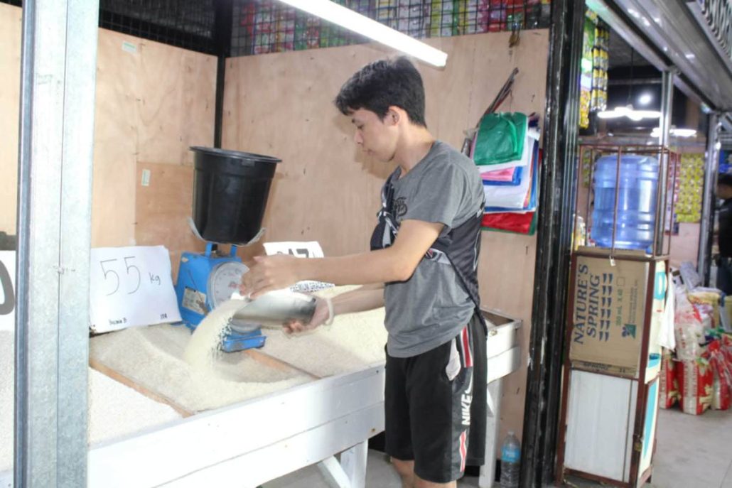 Ronel Comeda weighs rice in his Pototan, Iloilo stall. He laments the growing difficulty of budgeting amid unpredictable price swings and rising fuel costs. AJ PALCULLO/PN