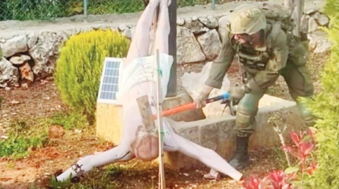 An Israeli soldier uses an implement to hit the face of an upturned statue of Jesus Christ in south Lebanon. The Israeli military said it viewed the soldier's actions with “great severity”. REUTERS