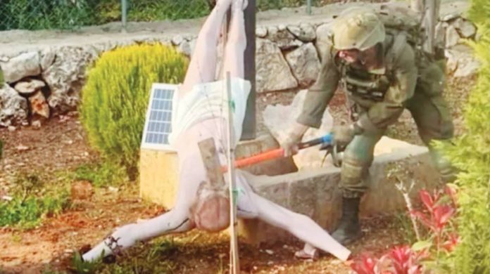 Israel soldiers An Israeli soldier uses an implement to hit the face of an upturned statue of Jesus Christ in southern Lebanon. REUTERS