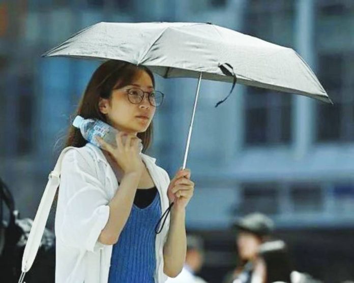 Japan copy A woman walking on the street shields herself with a parasol in Tokyo, Japan. David Mareuil/Anadolu via Getty Images
