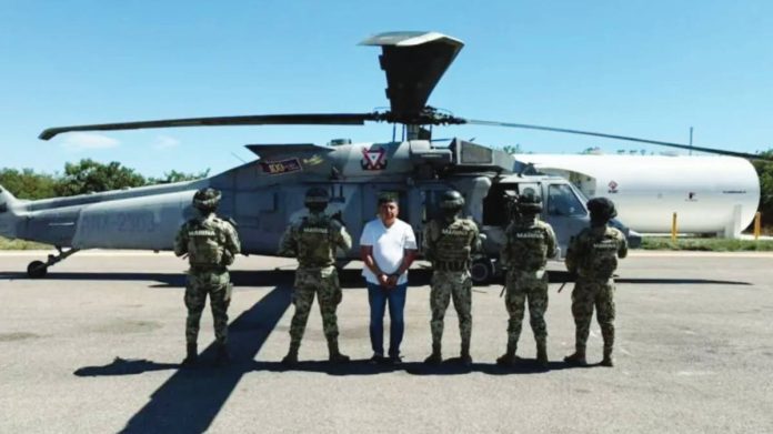 Mexico Members of Mexican Special Forces escort suspected drug cartel leader Audias Flores, known as “El Jardinero”, after his capture. Five officers are standing with their backs to the camera, to conceal their identities. Flores is facing the camera. After his capture, Flores was transported to a secure facility via helicopter. SEMAR VIA REUTERS