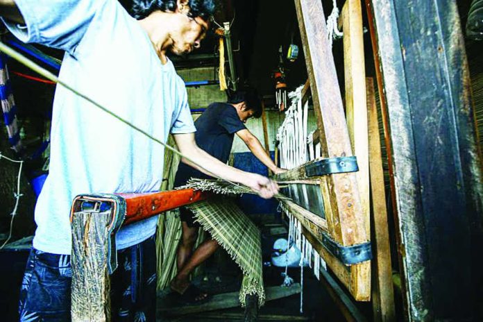 bamboo_industry_copy_compressed_resized Jun, 40, and Jerome, 21, weave blinds made from bamboo sticks and leaf midribs at a workshop in Pasig City on April 13, 2026. The Department of Agriculture is looking to avail of $300 million to $500 million from international financial institutions, citing the huge potential for engineered bamboo as an alternative material for construction. PNA PHOTO BY JOAN BONDOC