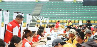 Regional Director Joselito G. Estember (standing, left) of the Department of Social Welfare and Development Region 6 oversees the distribution of cash relief to tricycle driver beneficiaries at the Passi City Arena in Passi City, Iloilo on Wednesday, April 8, 2026. He personally monitors the payout flow and implements an action plan to expedite the process for 2,600 transport sector workers affected by the ongoing economic crisis. DSWD REGION 6 PHOTO