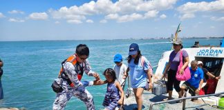 A Philippine Coast Guard personnel assists a young passenger as pilgrims and travelers disembark at a port in Guimaras during the Holy Week rush, part of intensified safety operations across Western Visayas. PHOTO FROM PCG- GUIMARAS STATION