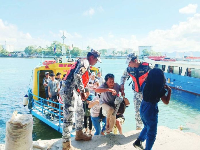 ime coastguard Philippine Coast Guard personnel assist passengers from Guimaras Island as they disembark from a motorboat upon arrival at a wharf in Iloilo City. Authorities are intensifying port operations for the Holy Week travel surge. PCG-ILOILO PHOTO