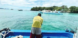 A mambabangka stands at the bow as boats continue to ply the Caticlan–Boracay route — his “No to Boracay Bridge” shirt reflecting a quiet but resolute stand to protect a livelihood anchored on the sea.