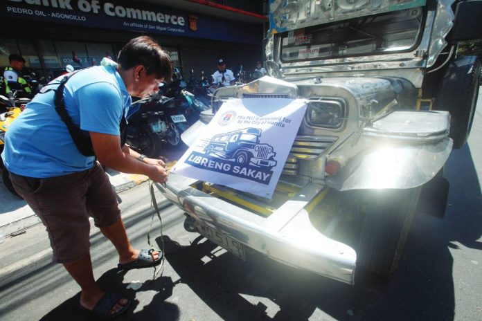 A driver puts a “Libreng Sakay” signage on his jeepney along Agoncillo Street in Manila. The city government of Manila pays a minimum P3,500 daily to participating drivers in exchange for providing free rides. PNA