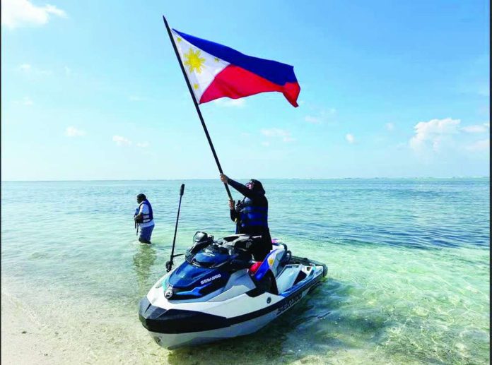 China_West_PH_Sea_copy_compressed_resized NO JOKE. Akbayan party-list’s Cong. Dadah Kiram Ismula arrives by jet ski at Pag-asa Cay 2 (Sandy Cay) on Sunday, May 3, 2026, and raises high the Philippine flag. This was the Atin Ito activist coalition’s fourth mission to the West Philippine Sea, challenging China’s trespassing into Philippine waters. PHOTO FROM THE ATIN ITO COALITION