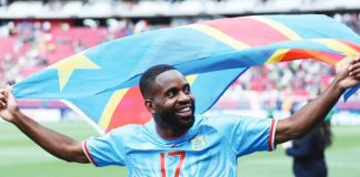 Congolese football player Cédric Bakambu celebrates with the national flag on a football pitch. The Democratic Republic of Congo has qualified for the FIFA World Cup for the first time since 1974. GETTY IMAGES