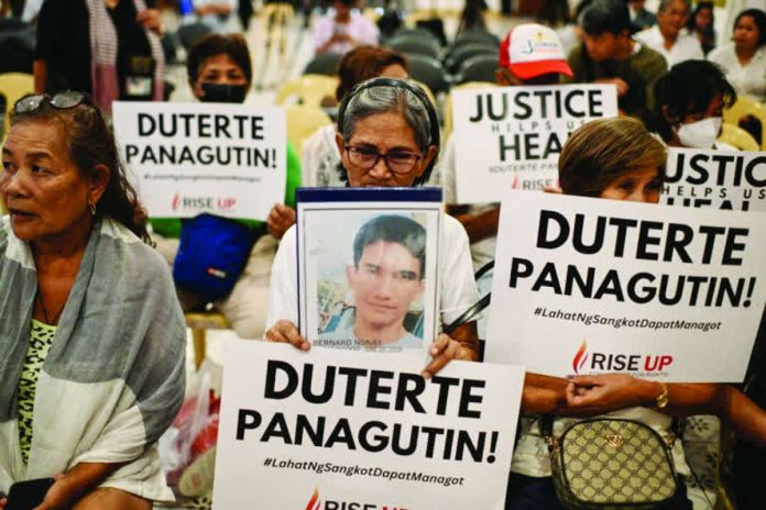 Duterte_ICC_copy_compressed_resized Relatives of war on drugs victims hold placards calling for justice minutes before the start of former President Rodrigo Duterte's hearing on the confirmation of charges on his alleged crimes against humanity case at the International Criminal Court, in this photo taken in Quezon City on February 23, 2026. REUTERS