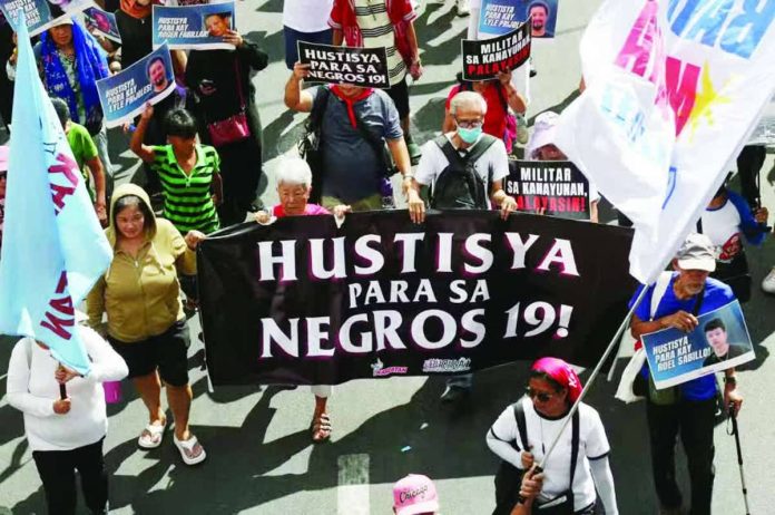 NEGROS KILLINGS. Marchers participating in the May Day protest in Manila carry a large banner demanding justice for 19 people killed in Toboso, Negros Occidental, during a military operation against New People’s Army rebels. PHOTO FROM NIÑO JESUS ORBETA