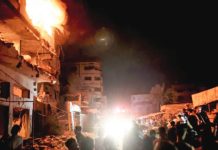People look on as fire burns in a building in central Gaza City. GETTY IMAGES