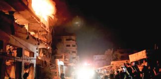 People look on as fire burns in a building in central Gaza City. GETTY IMAGES