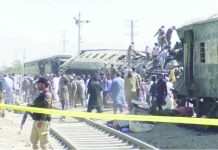 People gather at burnt-out and mangled train carriages that a bomb destroyed in Pakistan. BBC