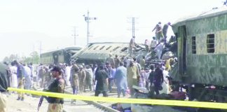 People gather at burnt-out and mangled train carriages that a bomb destroyed in Pakistan. BBC