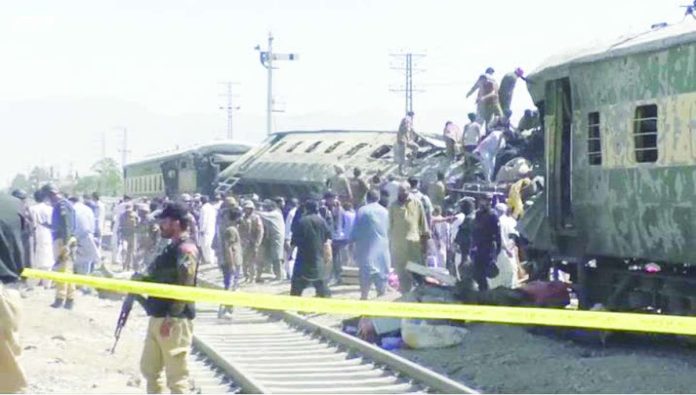 People gather at burnt-out and mangled train carriages that a bomb destroyed in Pakistan. BBC