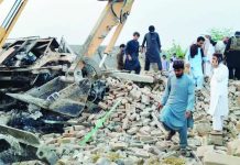 Pakistan car bomb attack kills 15 police officers People survey a blast scene as a digger moves rubble following a car bombing in Bannu, Pakistan. EPA