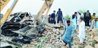 People survey a blast scene as a digger moves rubble following a car bombing in Bannu, Pakistan. EPA