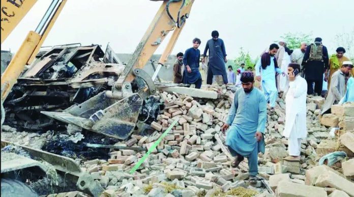 People survey a blast scene as a digger moves rubble following a car bombing in Bannu, Pakistan. EPA