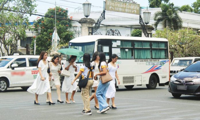 Pedestrians rush across the street in front of the historic Jaro Metropolitan Cathedral in Jaro, Iloilo City, as scorching heat gripped the city on Monday, May 18. The heat index soared to a blistering 48 degrees Celsius at noon, prompting growing concern from authorities over worsening urban heat conditions and the escalating risks posed by climate change. AJ PALCULLO/PN