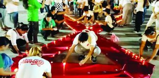 Volunteers, advocates, healthcare workers, and members of the LGBTQ community light candles forming the iconic red ribbon symbol during the 2026 AIDS Candlelight Memorial held at the Pavia, Iloilo municipal plaza on May 26, 2026 honoring lives lost to AIDS-related illnesses while promoting HIV awareness, acceptance, and the fight against stigma and discrimination against persons living with HIV. IME SORNITO/PN