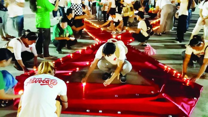 Volunteers, advocates, healthcare workers, and members of the LGBTQ community light candles forming the iconic red ribbon symbol during the 2026 AIDS Candlelight Memorial held at the Pavia, Iloilo municipal plaza on May 26, 2026 honoring lives lost to AIDS-related illnesses while promoting HIV awareness, acceptance, and the fight against stigma and discrimination against persons living with HIV. IME SORNITO/PN