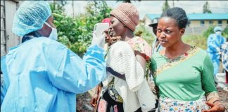 A health worker in protective gear carries out temperature screening for travelers at the Kanyaruchinya checkpoint near Goma, eastern Congo. ANADOLU VIA GETTY IMAGES