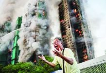 First charges laid over deadly Hong Kong fire A man holds on both hands, shouting in agitation, as long columns of smoke billow out from Hong Kong residential blocks in the background. The blaze at the Wang Fuk Court housing complex was the deadliest the city had seen in more than 70 years. REUTERS