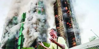 A man holds on both hands, shouting in agitation, as long columns of smoke billow out from Hong Kong residential blocks in the background. The blaze at the Wang Fuk Court housing complex was the deadliest the city had seen in more than 70 years. REUTERS