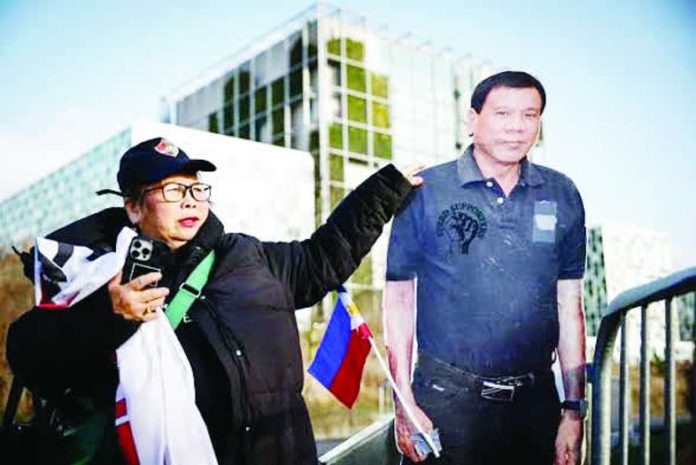 ICC_freezes_copy_compressed_resized A person stands by a life-size cardboard cutout of former president Rodrigo Duterte during a demonstration in his support outside the International Criminal Court, where he faces trial for charges of crimes against humanity, in The Hague. Photo by Simon Wohlfahrt / AFP