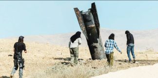 Israeli settlers stand next to part of an Iranian ballistic missile protruding from the ground in the Israeli-occupied West Bank. REUTERS