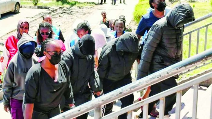 Kenya_copy_compressed_resized Several hooded and masked students, accompanied by adults, walk up courthouse steps under police escort. They are arson suspects in a fatal school fire. REUTERS