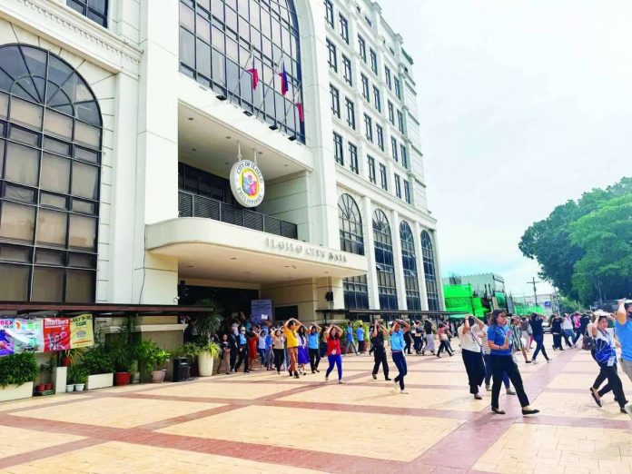 Mai_quake_drill_expose_(2)_compressed_resized TEST OF READINESS. Employees of the Iloilo City Government cover their heads while evacuating the city hall during the National Simultaneous Earthquake Drill on June 18. While the city government posted a faster evacuation time of five minutes and 58 seconds, disaster management officials noted that some employees failed to observe key earthquake response protocols. MAI LADIAO/PN