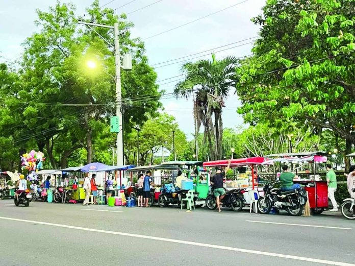 Ambulant vendors sell food and other items along North Capitol Road in Bacolod City. The Negros Occidental provincial government has requested the removal of vendors in the area, citing concerns over traffic, sanitation and security, while city officials maintain that the vendors are operating under permits issued pursuant to the city's Vending Regulation Ordinance. BCCO