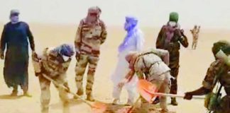 People, including several in military-style uniforms, use shovels to dig in a sandy desert area, with dust rising around them. AGADEZ GOVERNORATE/FACEBOOK