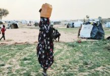 Sexual violence used as ‘weapon of war’ in Sudan A woman, with her back to the camera and carrying a drum on her head, is walking in a camp, with children seen not far from her. The conflict in Sudan has forced millions of people to flee their homes. REUTERS