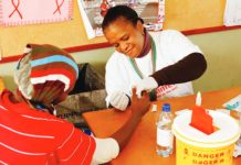 A South African woman is testing another person for human immunodeficiency virus at a clinic. GETTY IMAGES