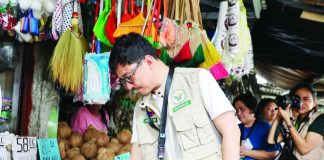 Regional Executive Director Dennis Arpia of the Department of Agriculture in Western Visayas checks rice stocks and prevailing market prices during an inspection at a public market in Iloilo City on June 1, 2026. The monitoring aims to ensure that retailers and traders comply with the P50-per-kilogam price cap on five-percent broken imported rice.