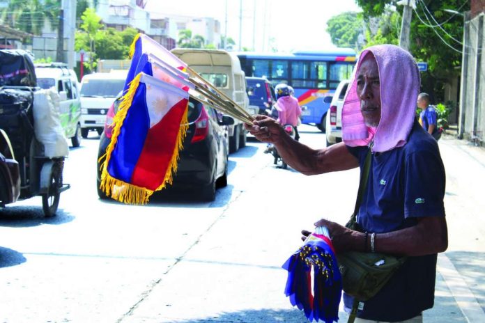 neljoy_flag_vendors_-_Eddie_Custodio_compressed_resized For Eddie Custodio from Lapuz, Iloilo City, selling flags is a tradition spanning more than 30 years. He travels between Lapuz, Jaro, and other locations, carrying his inventory and patiently waiting for customers. “Tatlo akon nga mga kabataan. Ang pagbaligya ko sini nakabulig man gamay kag nakatapos na sila eskwela,” he said proudly.