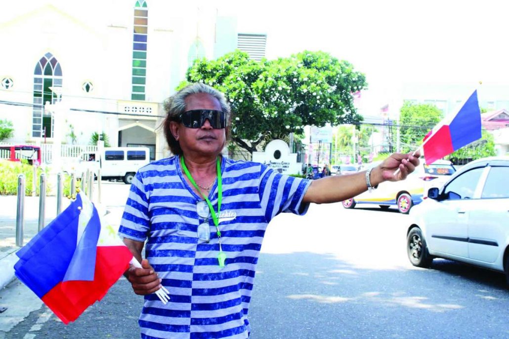 Ricardo Parian of Barangay San Isidro Relocation Site in Jaro, Iloilo City says Philippine flag-selling will never make him rich. Yet for him every sale matters, every peso earned helps put food on the table and contributes to the education of his child. “Isa malang sa isa ka tuig. Samtang buhi pa ko, mabaligya ko eh,” he adds.