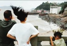 China evacuates nearly 2M people as powerful typhoon makes landfall A man, woman and child stand behind a cemented barrier, looking at muddy waters in a coastal region. Typhoon Bavi has passed through the coastal village of Diaocaocun in Zhejiang province, China. REUTERS