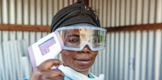A healthcare worker wears goggles and a mask pulled down from her mouth, and holds up a thermometer. Ebola has been confirmed in three provinces of Congo so far – Ituri, North Kivu and South Kivu. GETTY IMAGES
