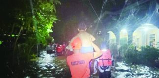A Coast Guard rescuer carries a child through floodwaters as emergency responders escort displaced residents to safer ground in Hamtic, Antique. SN1 SURIAGA, PHILIPPINE COAST GUARD VIA HAZEL P. VILLA
