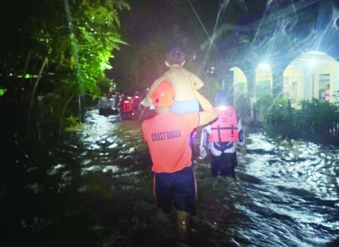 A Coast Guard rescuer carries a child through floodwaters as emergency responders escort displaced residents to safer ground in Hamtic, Antique. SN1 SURIAGA, PHILIPPINE COAST GUARD VIA HAZEL P. VILLA