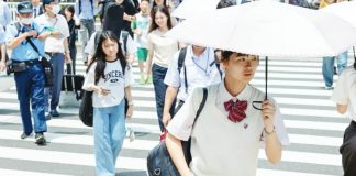 Japanese people walk over a crossroad on a hot summer day. GETTY IMAGES