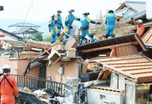 Rescue workers in overalls stand on top of a collapsed house at Kumamoto prefecture on Kyushu Island, Japan. A strong earthquake caused widespread damage to houses and power lines across Kumamoto. JIJI PRESS / AFP VIA GETTY IMAGES