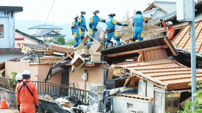 Japan Rescue workers in overalls stand on top of a collapsed house at Kumamoto prefecture on Kyushu Island, Japan. A strong earthquake caused widespread damage to houses and power lines across Kumamoto. JIJI PRESS / AFP VIA GETTY IMAGES